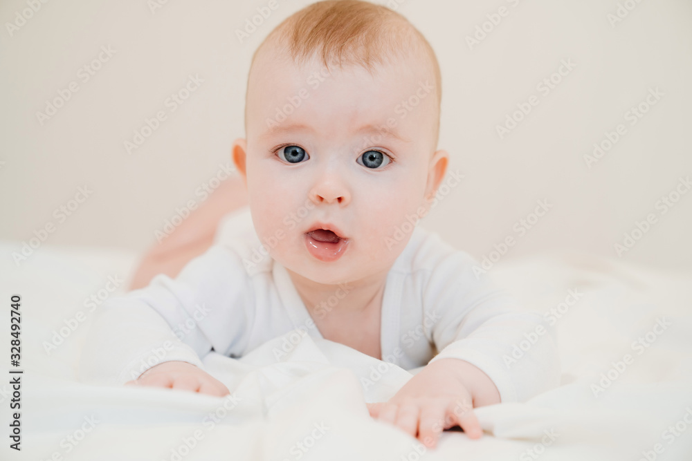 baby in white clothes lying on paunch on bed