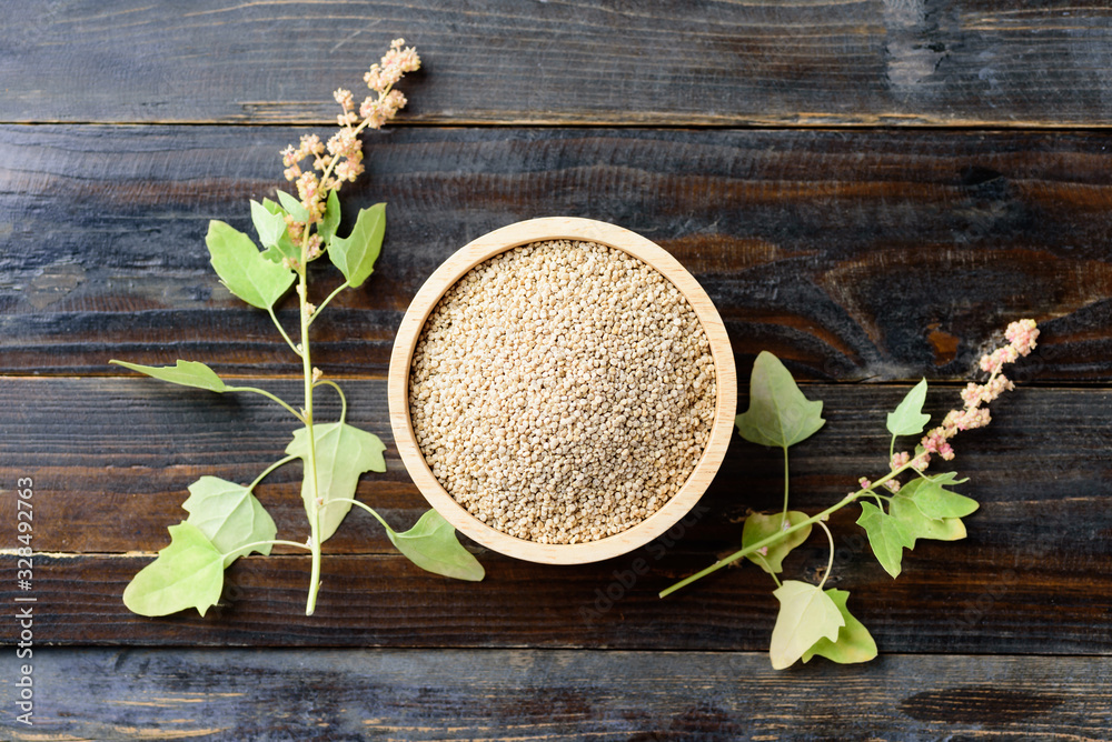 Organic raw brown quinoa seed (Chenopodium quinoa) in a bowl and quinoa plant on wooden background, healthy food, Top view - obrazy, fototapety, plakaty 