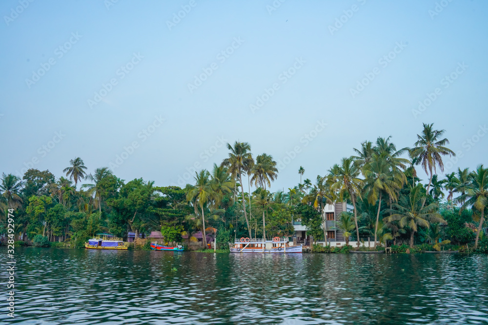 Obraz premium River side view with coconut tree and house in alleppey. Kerala 