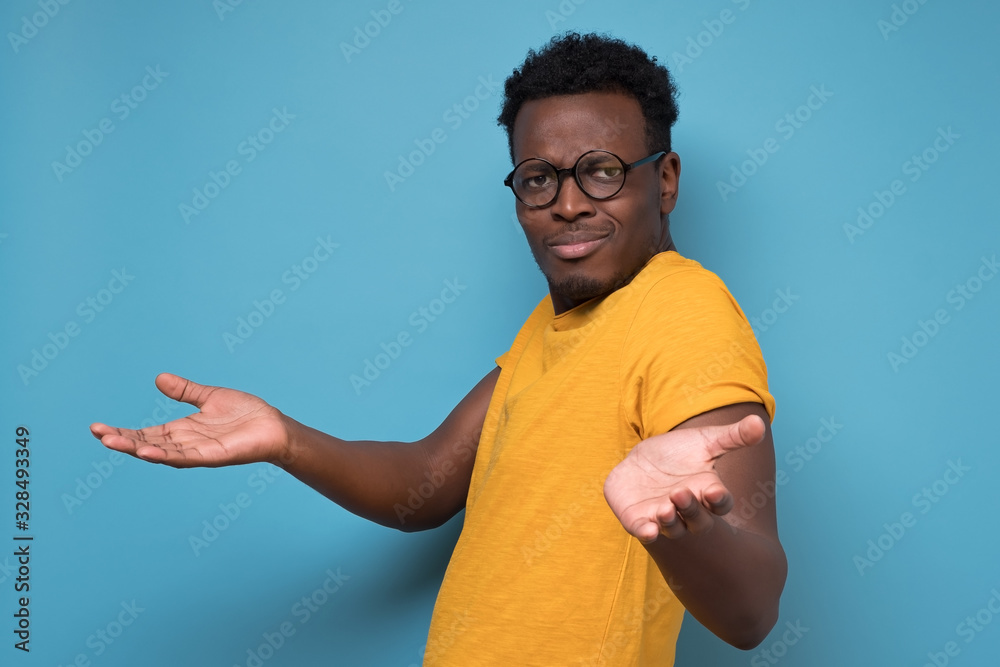 Unhappy man in glasses making arms out asking what is the problem who cares Unhappy man in glasses making arms out asking what is the problem who cares