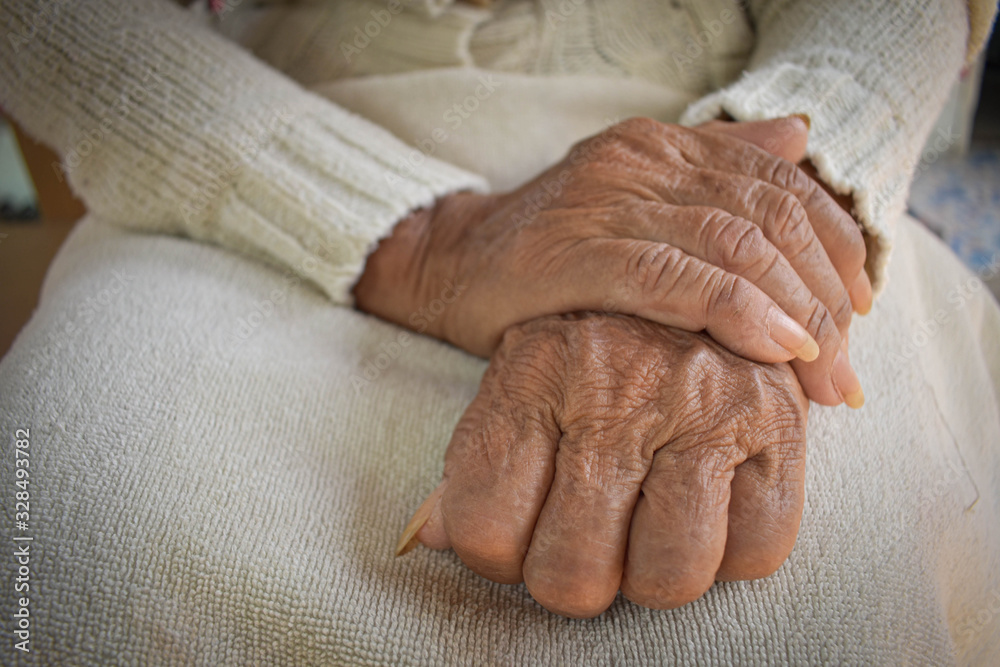  Wrinkled hand of the elderly is placed on the lap