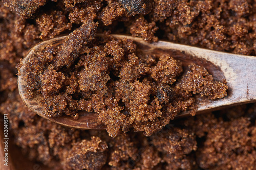 Dark muscovado sugar, also called Barbados sugar, khandsari, or khand, in wooden spoon photo