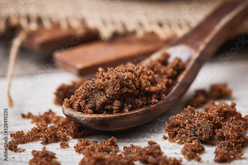 Dark muscovado sugar, also called Barbados sugar, khandsari, or khand, in wooden spoon