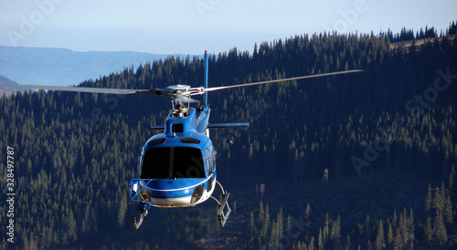 Blue helicopter above the forest