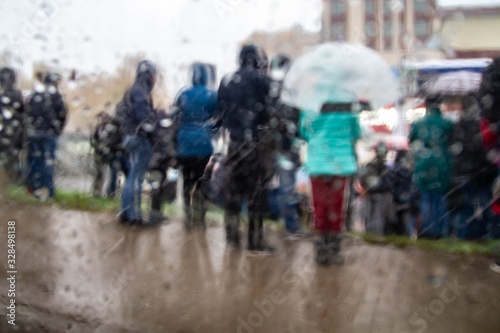 Blurred background. A crowd of people standing in the rain and snow. Autumn, winter weather. © Olga