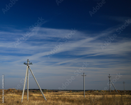 electric poles in an open field against a blue sky