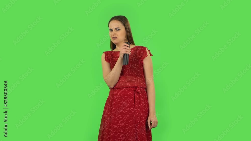 Tender girl in red dress with TV remote in her hand, switching on TV. Green screen Tender girl in red dress with TV remote in her hand, switching on TV. Green screen