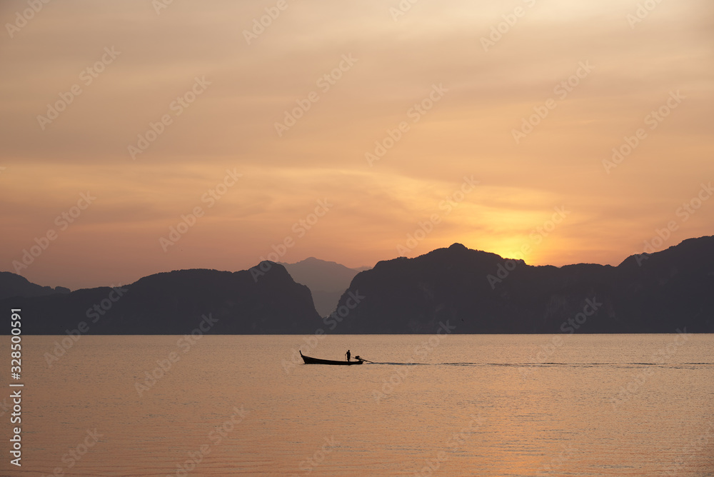 A fisherman on longtail boat against sunrise background A fisherman on longtail boat against sunrise background