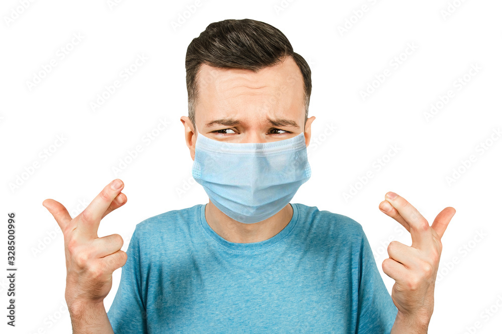 Portrait young man with cross fingers. wearing protective face mask prevent virus infection, white isolated background Portrait young man with cross fingers. wearing protective face mask prevent virus infection, white isolated background