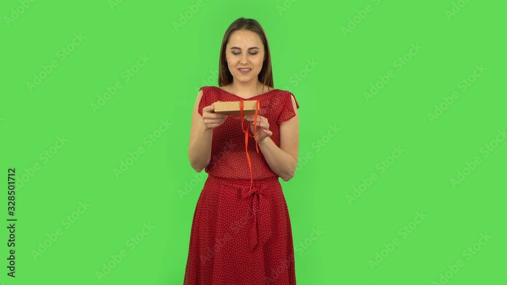 Tender girl in red dress is opening the gift, very surprised and upset. Green screen Tender girl in red dress is opening the gift, very surprised and upset. Green screen