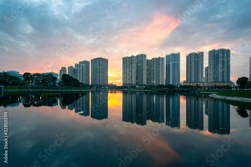 Buildings with reflections on lake at sunset at Thanh Xuan park. Hanoi cityscape at twilight period