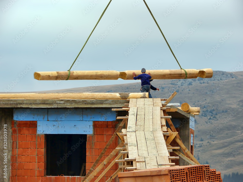 Naklejka premium Workers fix the beam on the construction