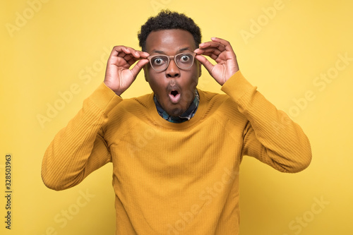 Foto man looks into camera, rounds lips with surprisment, stares through spectacles