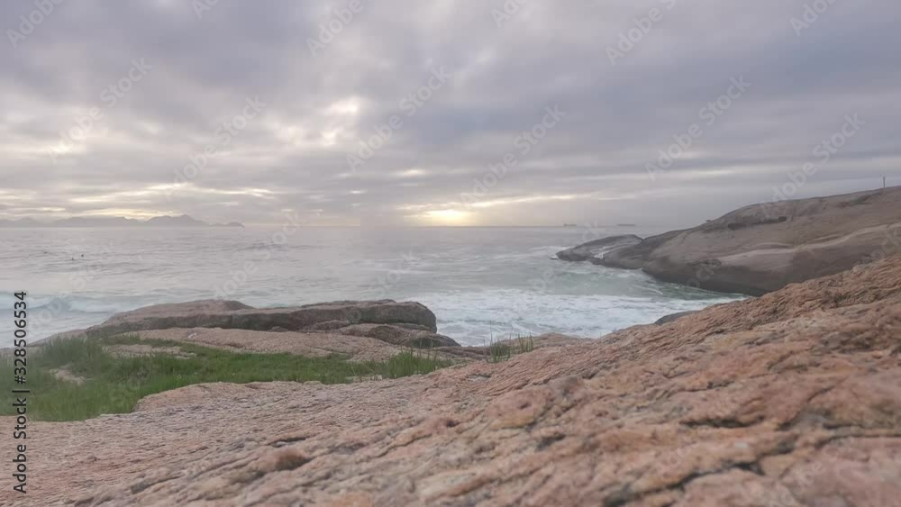 Time lapse with Jacobs ladder on overcast sunrise with waves coming in at the Arpoador rock formation in Rio de Janeiro, Brazil Time lapse with Jacobs ladder on overcast sunrise with waves coming in at the Arpoador rock formation in Rio de Janeiro, Brazil