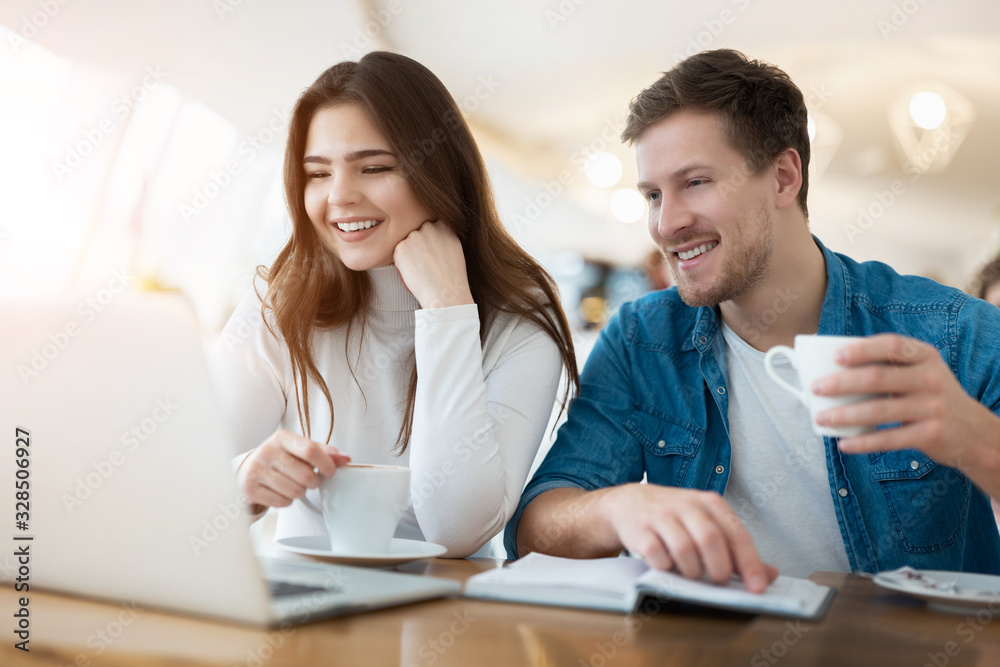 two young colleagues brunette woman and handsome man working in laptop during lunch break at cafe, both smiling and looking happy, teamwork and multitasking concept two young colleagues brunette woman and handsome man working in laptop during lunch break at cafe, both smiling and looking happy, teamwork and multitasking concept