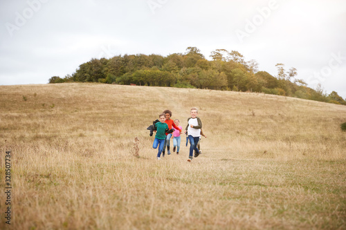 Front View Of Group Of Children On Outdoor Activity Camping Trip Running Down Hill