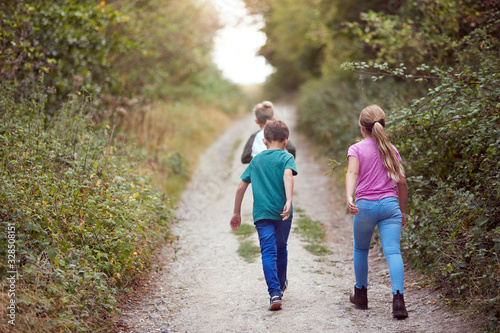 Rear View Of Children On Outdoor Activity Camping Trip Walking Along Countryside Path