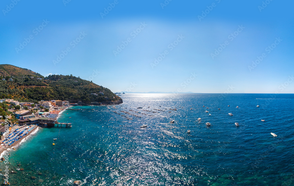 Aerial view of rocky beach, coastline of the village of Nerano. Private and wild beaches of Italy. Turquoise, blue surface of the water. Vacation and travel concept. Boats on raid. Copy space