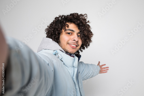 Young handsome curly man take selfie isolated on white background © dianagrytsku