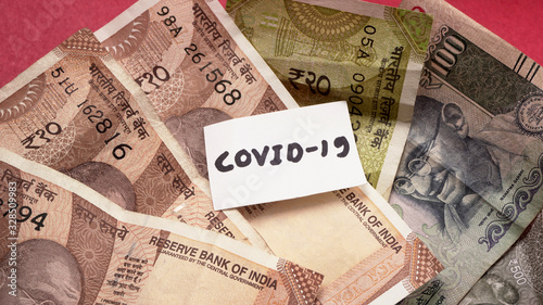 Notepad with words CORONA VIRUS or COVID-19 on indian currency concept of Economy and financial markets affected by corona virus. flat lay, Space for text.