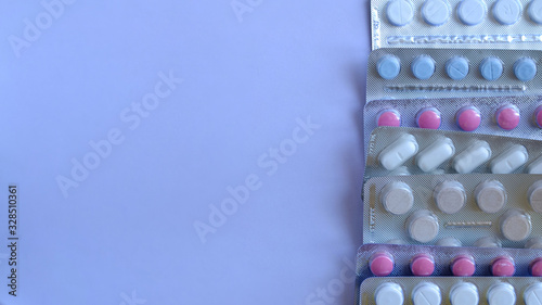 Pills in a row with copy space a top view on a lilac background.