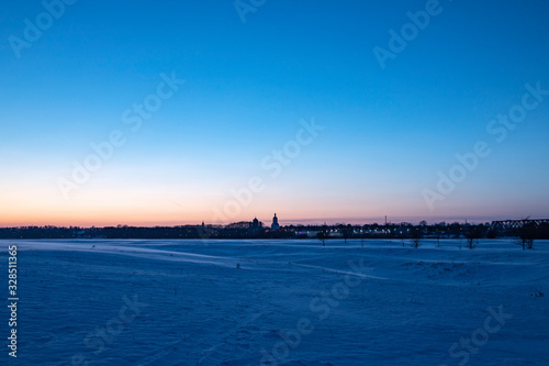 Wallpaper Mural Snowy plain under the sunset sky. Bell tower small town skyline.  Torontodigital.ca