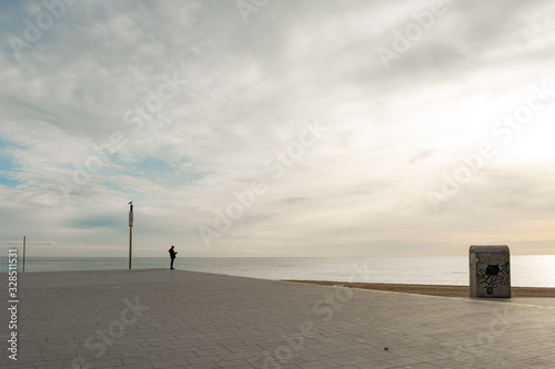 Fototapeta Naklejka Na Ścianę i Meble -  Hombre mirando el amanecer en la playa. Barcelona, España.