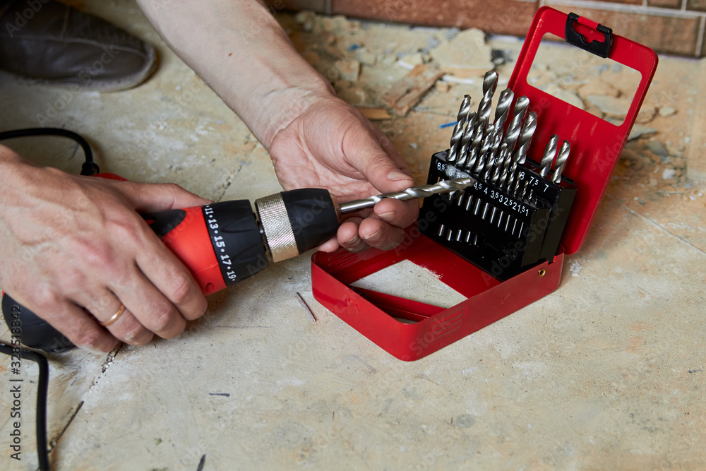 sets the Drill bit in the drill,hands take the drill bit and install in