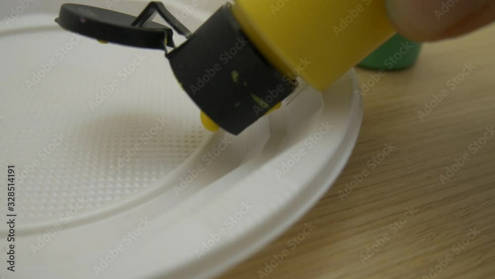 Poured acrylic yellow paint on a plastic plate on a wood table. Poured acrylic yellow paint on a plastic plate on a wood table.
