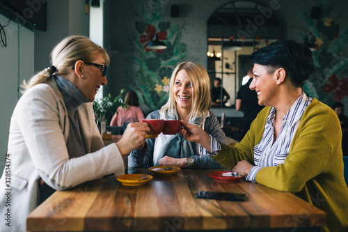 Behang woman friends on coffee break at cafe, cheers with coffee