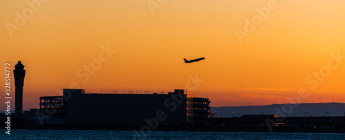 セントレアの夕景・オレンジ色の空と管制塔と離陸する飛行機のシルエット