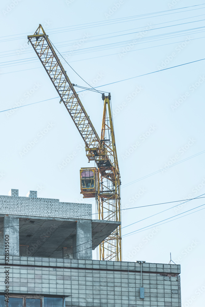 Fototapeta premium Construction site background. Hoisting crane and new multi-storey building. Industrial background.