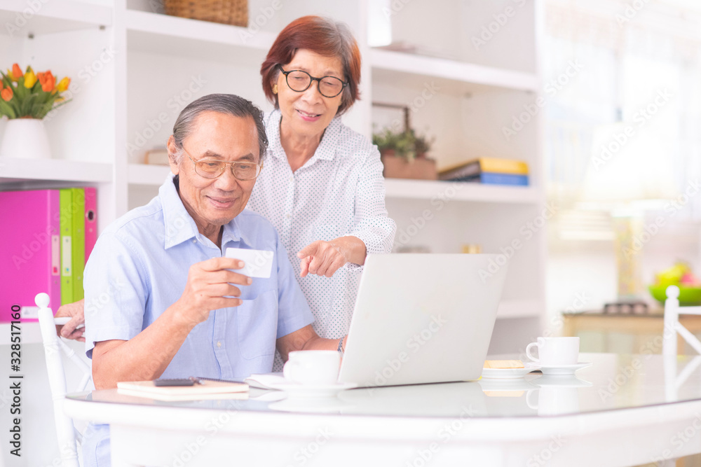 Asian senior couple using credit card for online shopping or internet banking. Old peoples with communication technology devices Asian senior couple using credit card for online shopping or internet banking. Old peoples with communication technology devices