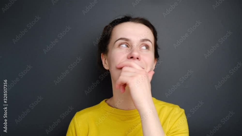 Cheerful positive young woman keeps fingers crossed, waits for special moment, closes eyes in anticipation, dressed yellow sweater, isolated on grey wall. Positive human emotions, attitude concept