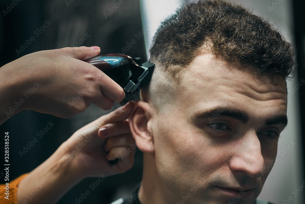 in the hands of a hairdresser a hair clipper. A girl does a hairstyle