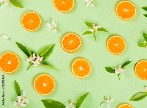  Slices of orange fruit and blossom with leaves.