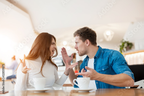 young couple beautiful woman and handsome man fighting, having argument while drinking coffee in cafe during lunch time break, problematic relationships concept