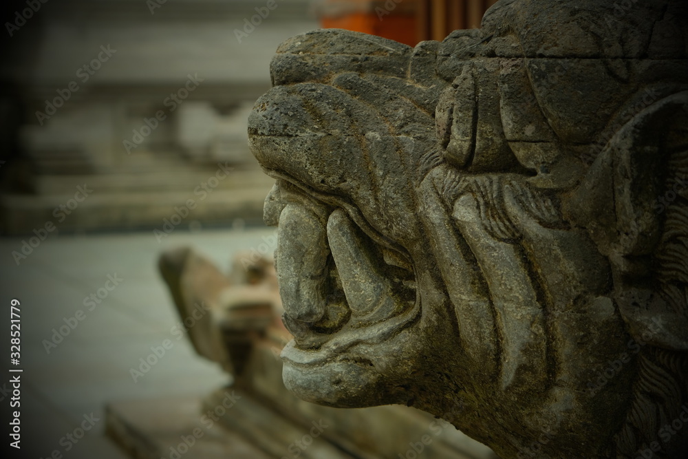 Part of a lion sculpture in profile in a Balinese temple with teeth and eyes.