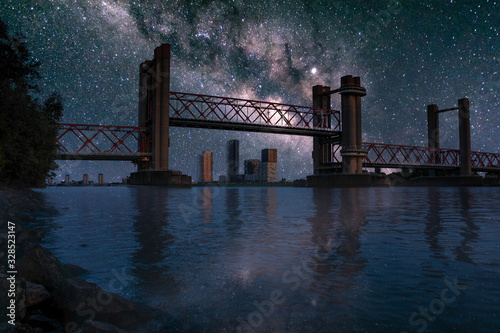 Spijkenisse bridge at night with milky way. River Maas waterfront view of open bridge part and the skyline of Spijkenisse on the background. Photomanipulation