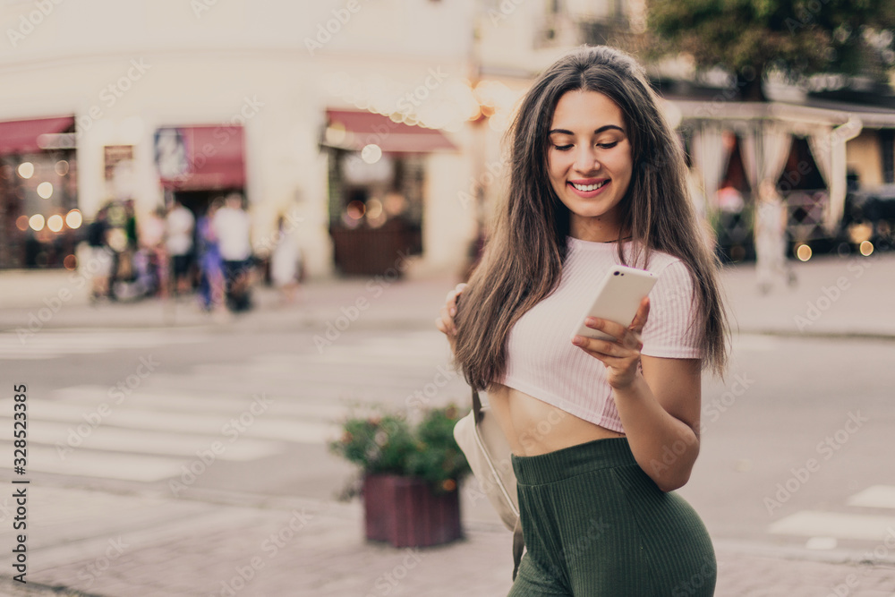 Woman using phone on the street in summer day.