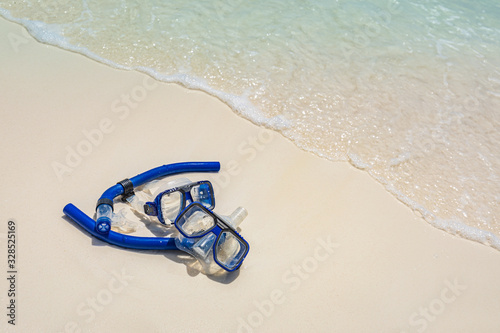 Diving goggles and snorkel gear on white sand near beach. Summer vacation and recreational travel background