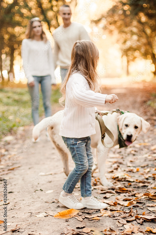 Little beautiful girl and parents walking with dog labrador in the park. Little beautiful girl and parents walking with dog labrador in the park.