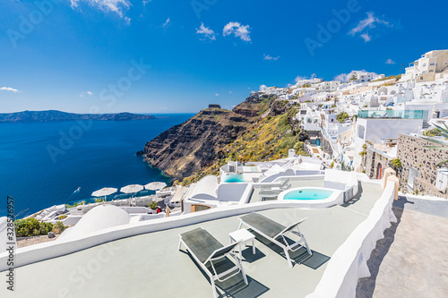 White architecture on Santorini island, Greece. Beautiful landscape with sea view. Luxury summer travel and vacation background. Romantic couple scene, loungers over pools and amazing summer landscape