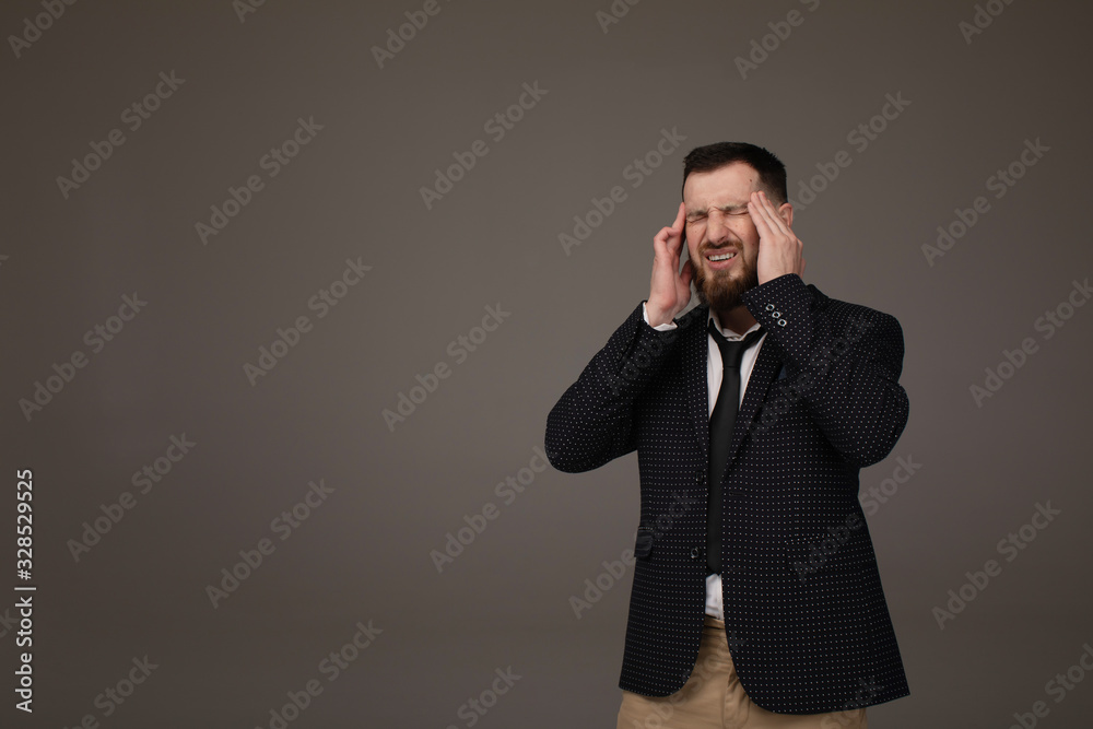 Young handsome bearded business man wearing suit over grey background with hand on headache because stress. Suffering migraine. Young handsome bearded business man wearing suit over grey background with hand on headache because stress. Suffering migraine.