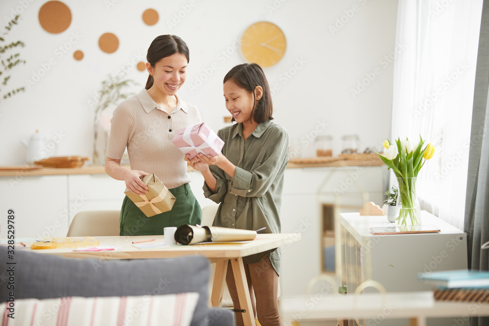Horizontal shot of happy young Asian woman and teen girl preparing gift boxes for Mothers Day holiday, copy space Horizontal shot of happy young Asian woman and teen girl preparing gift boxes for Mothers Day holiday, copy space