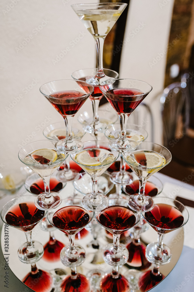 Pyramid of glasses with Martini cocktail for a festive reception at the wedding on the table. Cosmopolitan cherry cocktail Isolated. Pyramid of glasses with Martini cocktail for a festive reception at the wedding on the table. Cosmopolitan cherry cocktail Isolated.