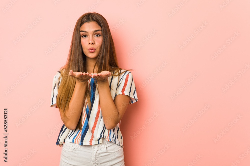 Young slim woman folding lips and holding palms to send air kiss. Young slim woman folding lips and holding palms to send air kiss.