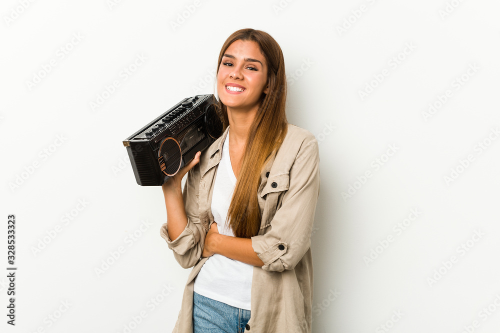 Young caucasian woman holding a guetto blaster laughing and having fun. Young caucasian woman holding a guetto blaster laughing and having fun.