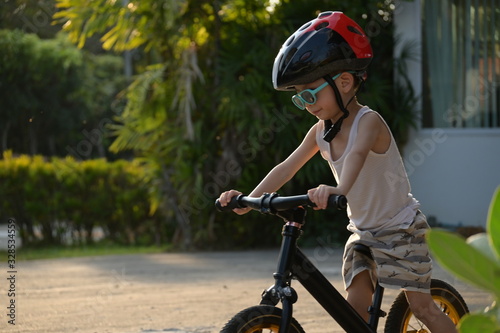 Fototapeta Naklejka Na Ścianę i Meble -  happy cute boy wear sunglasses and sport helmet playing balance bike exercise in the morning day