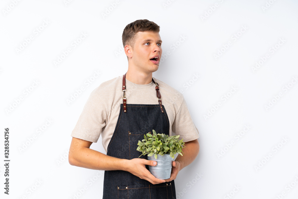 Young handsome man over isolated white background taking a flowerpot Young handsome man over isolated white background taking a flowerpot